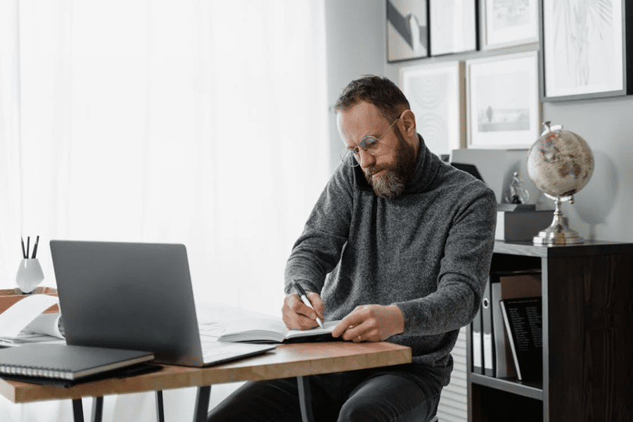 Man working at a desk on offshore strategies, surrounded by books and a globe, illustrating asset protection methods.