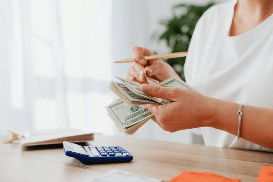 A person holding cash near a calculator, illustrating financial estate planning and wealth management processes.